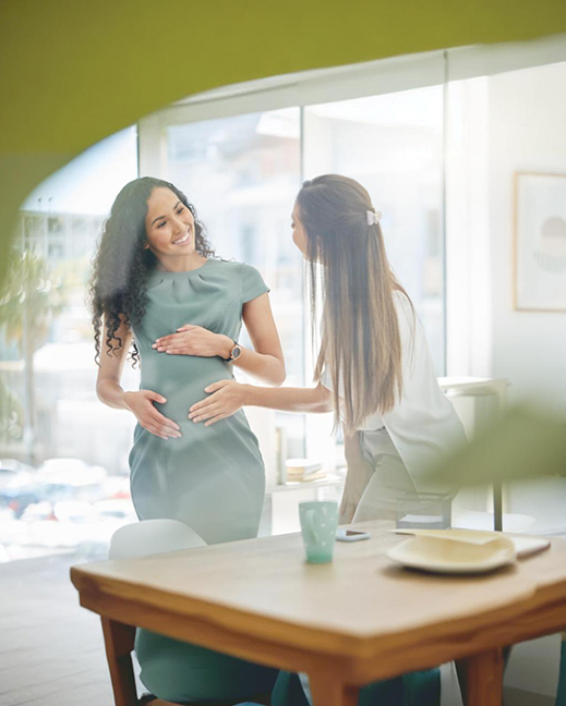 Pregnant woman standing outdoors, smiling at the camera